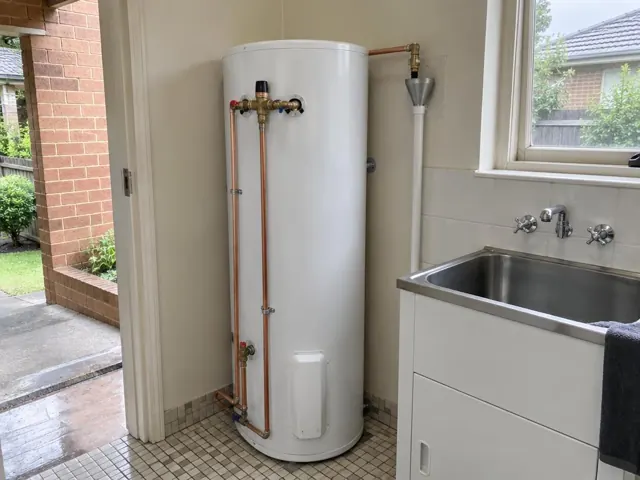 Indoor hot water tank beside a stainless sink and tiled laundry floor in a home in Strathfield